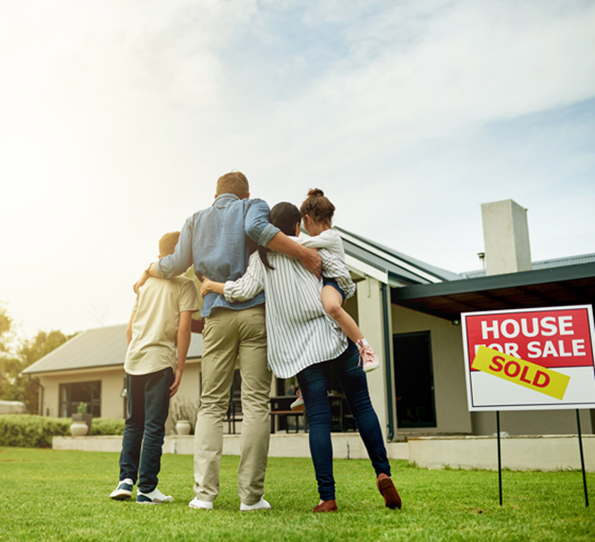 Family-standing-on-lawn-of-newly-bought-home