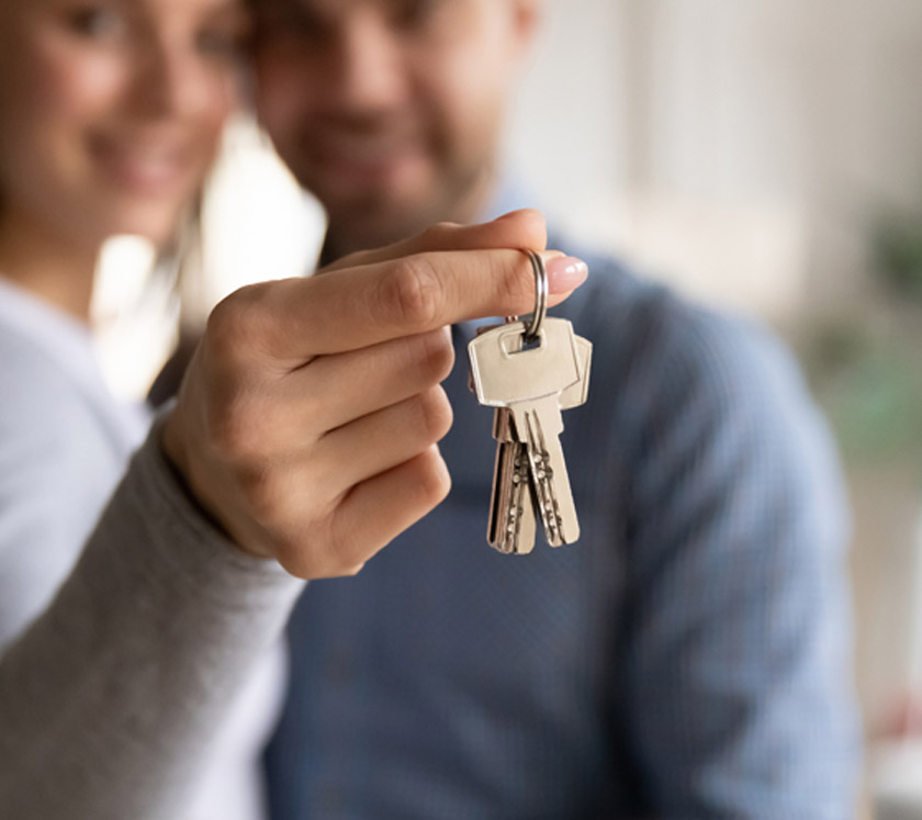 Woman-holding-keys-to-new-home-and-standing-next-to-young-man